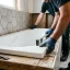 Handyman caulking the seam around a new bathtub during a Barrie bathtub replacement