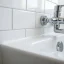 Close-up of a smooth white caulk line where bathtub meets tiled wall