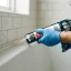 Gloved hands running a bead of caulk along a kitchen countertop seam