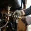 Gloved hands tightening a new kitchen faucet under the sink basin