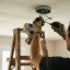 Handyman wiring a ceiling light fixture from a step ladder