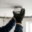 Handyman mounting a smoke detector to the ceiling with a drill