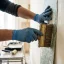 Handyman smoothing a strip of wallpaper onto the wall with a brush