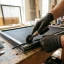 Handyman pressing new mesh into a window screen frame with a roller